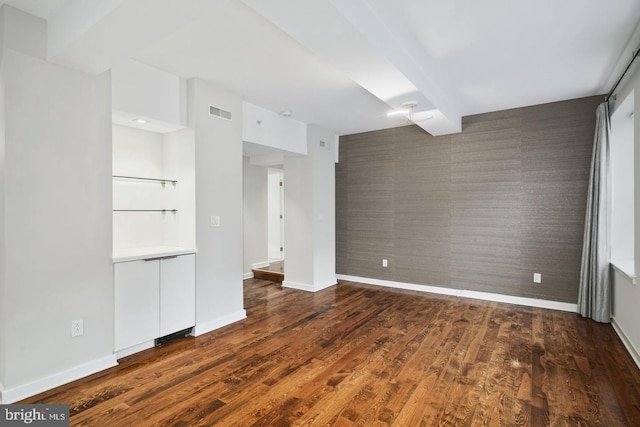 unfurnished living room featuring beamed ceiling and dark hardwood / wood-style floors