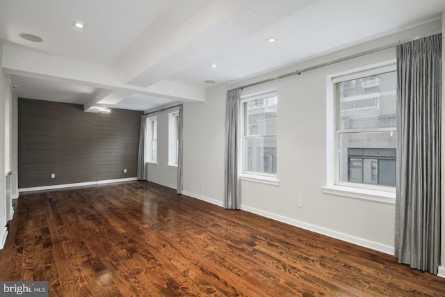 empty room featuring dark wood-type flooring and beamed ceiling