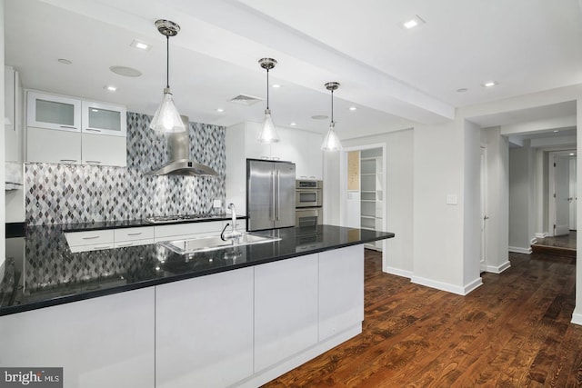 kitchen featuring white cabinetry, decorative light fixtures, wall chimney exhaust hood, and appliances with stainless steel finishes