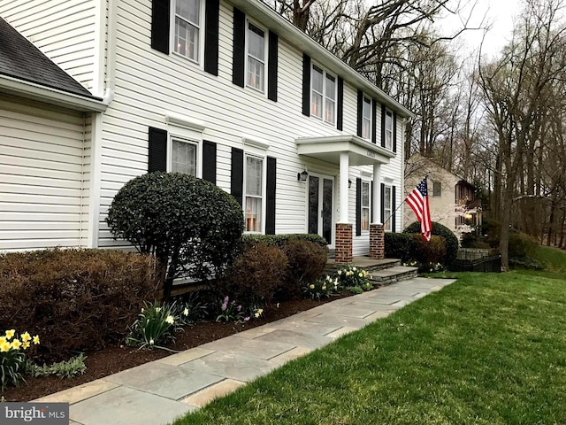 exterior space featuring a shingled roof and a yard