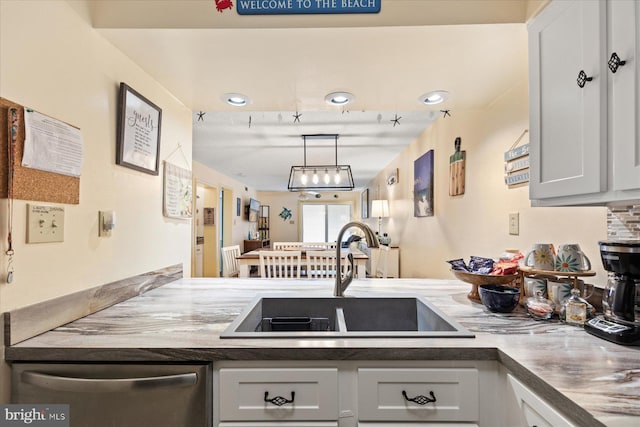 kitchen with sink, stainless steel dishwasher, white cabinets, and decorative light fixtures