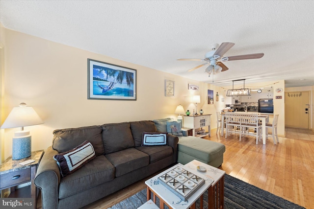 living room featuring ceiling fan, hardwood / wood-style floors, and a textured ceiling