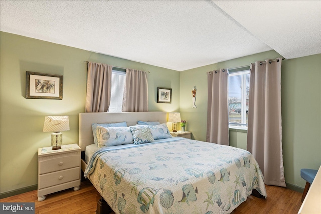 bedroom with multiple windows, a textured ceiling, and light hardwood / wood-style floors