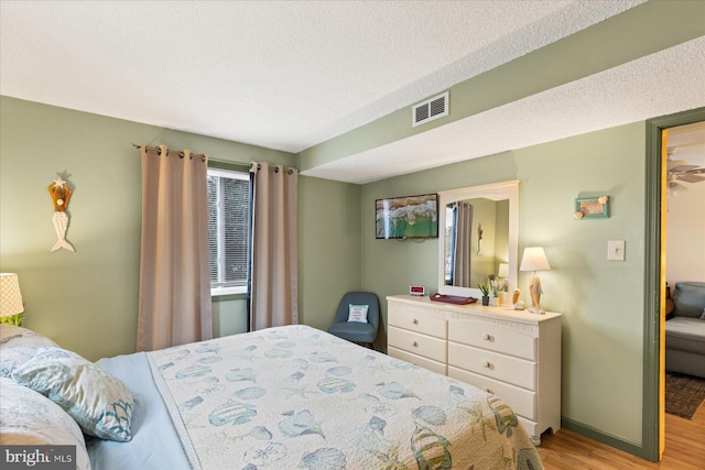 bedroom featuring light hardwood / wood-style floors and a textured ceiling