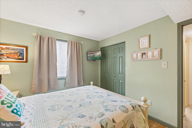 bedroom with light hardwood / wood-style floors, a closet, and a textured ceiling