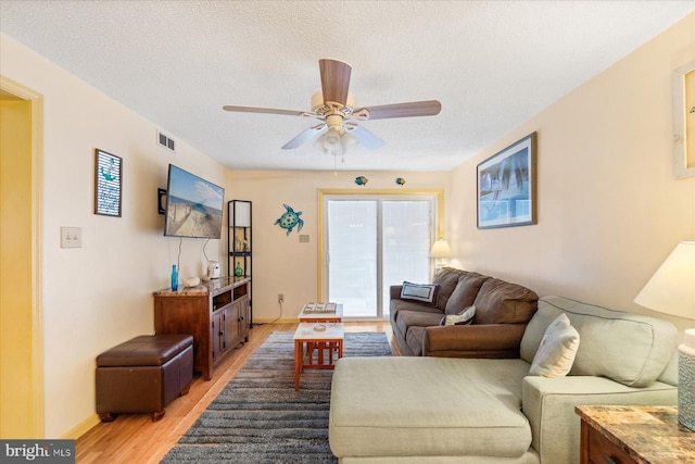 living room with ceiling fan, wood-type flooring, and a textured ceiling