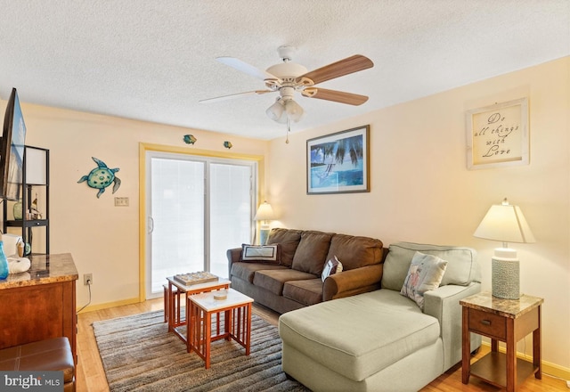 living room featuring hardwood / wood-style flooring, ceiling fan, and a textured ceiling