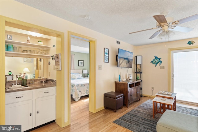 living room with ceiling fan, sink, a textured ceiling, and light hardwood / wood-style floors