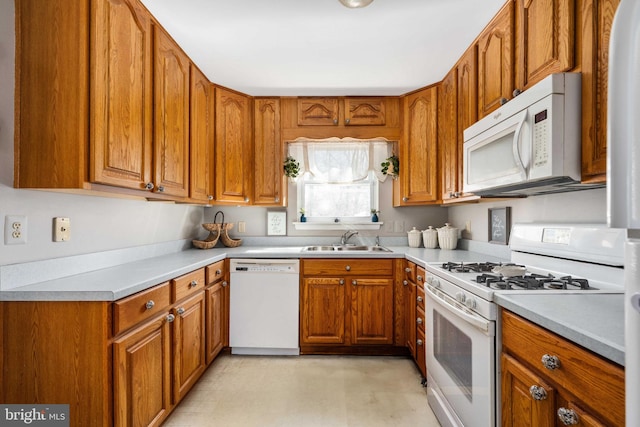 kitchen with white appliances, brown cabinetry, light countertops, and a sink