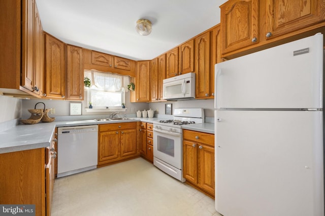 kitchen featuring white appliances, light floors, a sink, light countertops, and brown cabinets