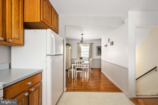 kitchen with light wood-type flooring, light countertops, brown cabinetry, and freestanding refrigerator