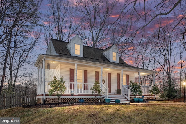 view of front of house featuring covered porch, roof with shingles, a front yard, and fence