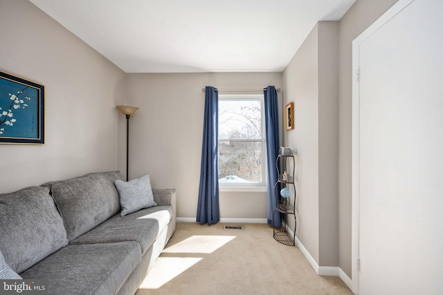 living area with baseboards, light carpet, and visible vents