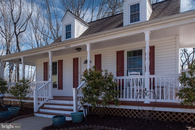 doorway to property featuring a porch and a shingled roof