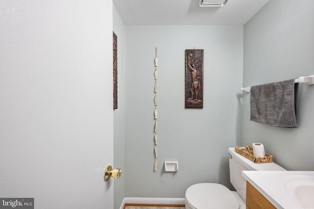 half bath featuring vanity, toilet, and baseboards