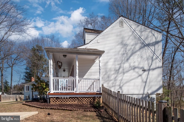 view of side of property featuring a porch and fence