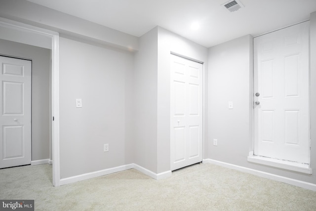 unfurnished bedroom featuring light carpet, visible vents, and baseboards