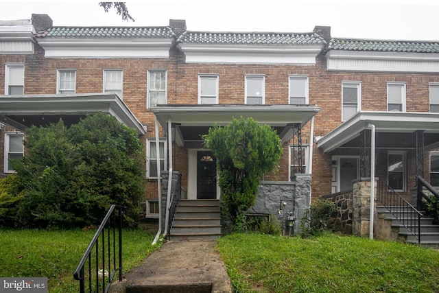 townhome / multi-family property with brick siding and a front lawn