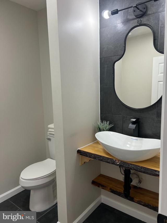 bathroom featuring toilet, tile patterned flooring, baseboards, and a sink