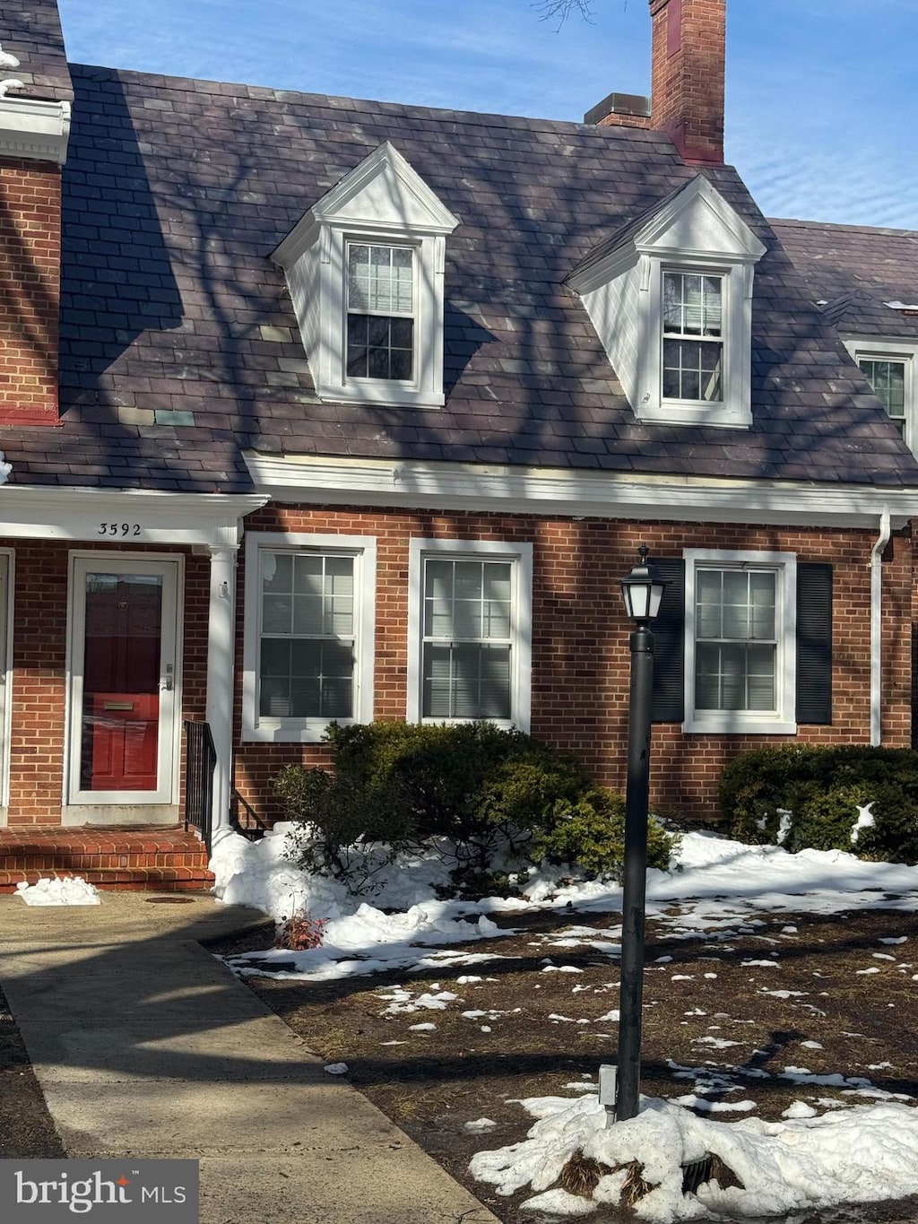 view of front of house with entry steps, a chimney, and brick siding