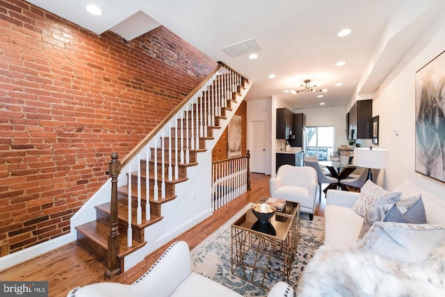 living room with hardwood / wood-style flooring and brick wall