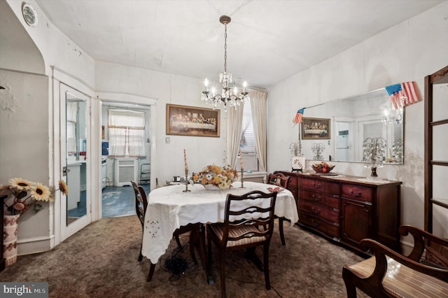 dining space with an inviting chandelier and dark colored carpet