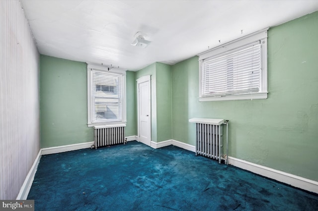 empty room with dark colored carpet and radiator heating unit