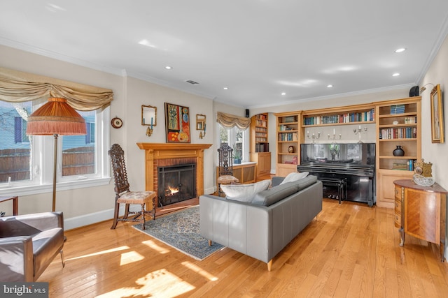 living room with light wood-type flooring, ornamental molding, and a brick fireplace