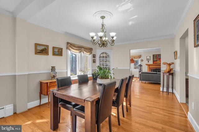 dining area featuring baseboard heating, light hardwood / wood-style flooring, a chandelier, and ornamental molding