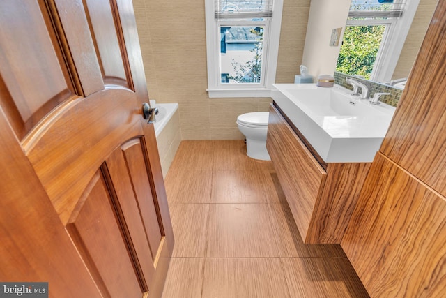 bathroom featuring tile walls, vanity, toilet, and tile patterned floors