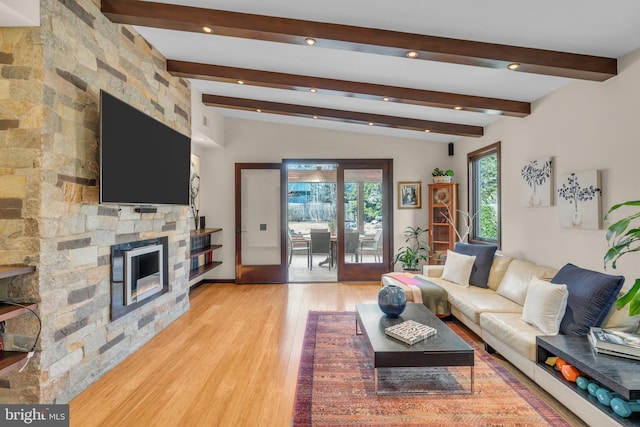 living room featuring a fireplace, light hardwood / wood-style floors, and beam ceiling