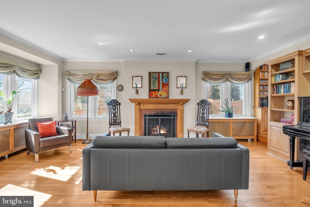 living room featuring light wood-type flooring, a brick fireplace, and a healthy amount of sunlight