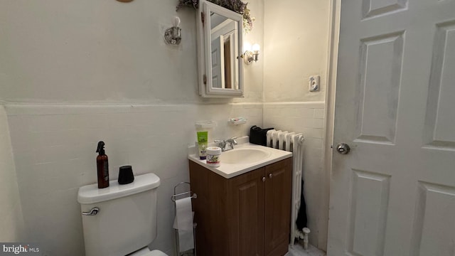 bathroom with vanity, radiator heating unit, tile walls, and toilet