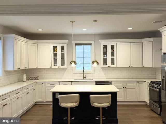 kitchen with appliances with stainless steel finishes, sink, white cabinetry, and hanging light fixtures