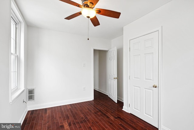 unfurnished bedroom featuring dark wood-style floors, visible vents, ceiling fan, and baseboards