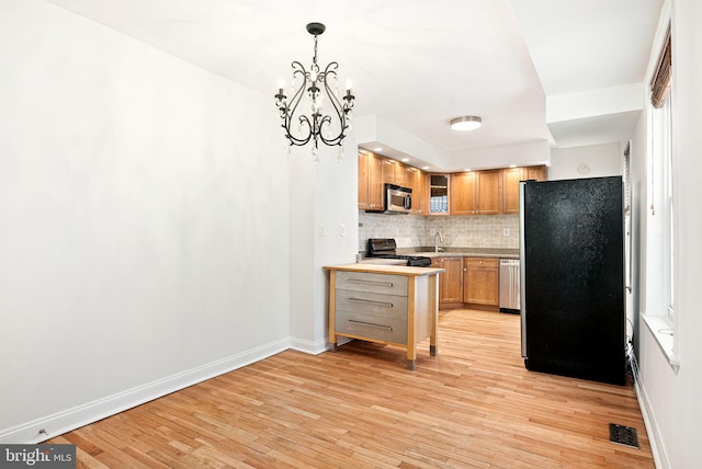 kitchen featuring stainless steel appliances, visible vents, light countertops, tasteful backsplash, and glass insert cabinets