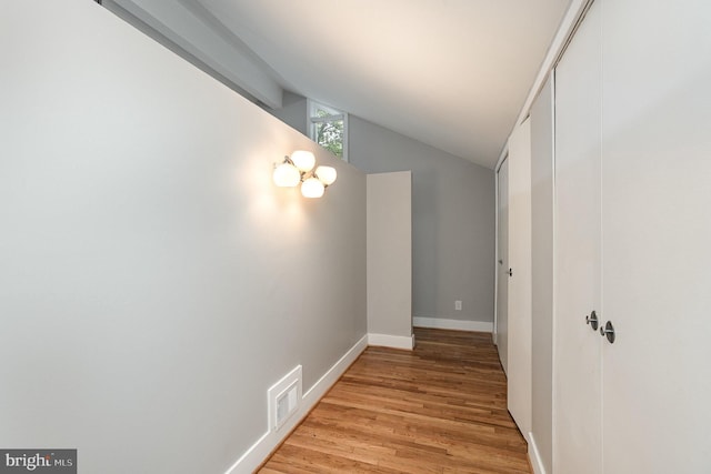 hall with lofted ceiling and light hardwood / wood-style flooring