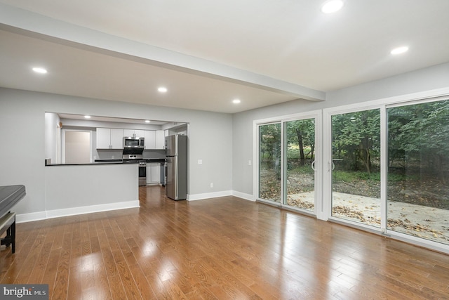 unfurnished living room featuring beam ceiling and light wood-type flooring