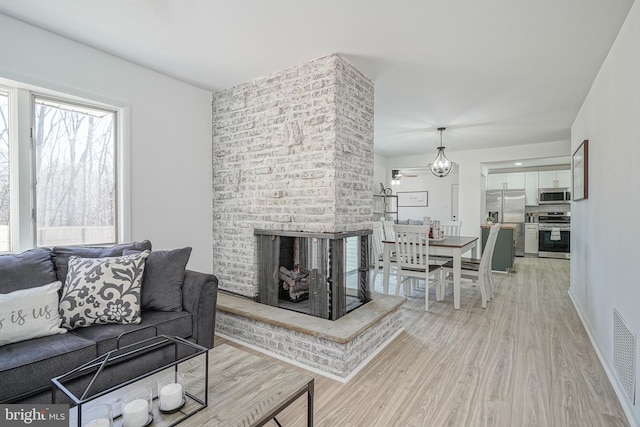 living room with a brick fireplace and light hardwood / wood-style flooring