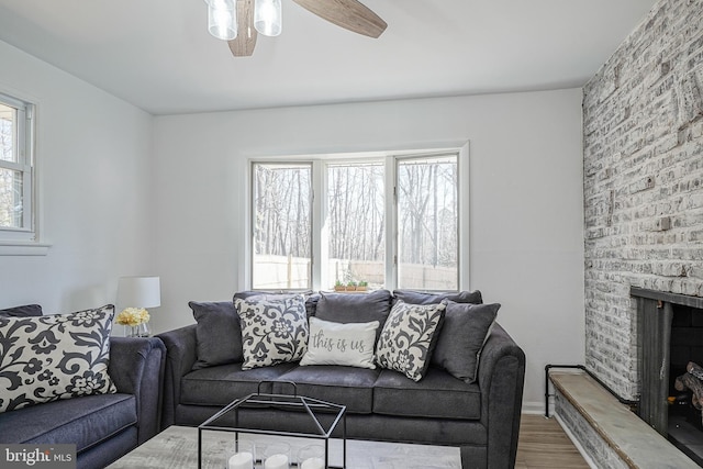 living room with a brick fireplace, hardwood / wood-style flooring, a wealth of natural light, and ceiling fan