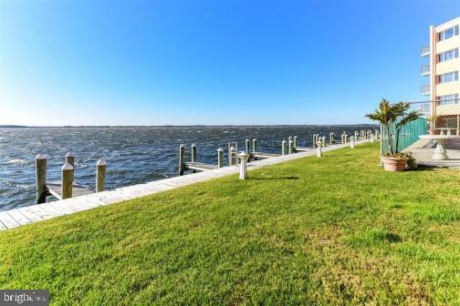 dock area with a water view and a lawn