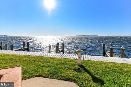 view of dock featuring a water view and a yard