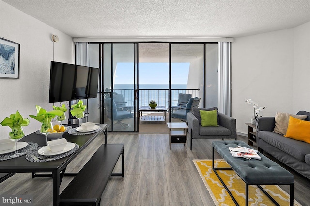 living room with a textured ceiling, wood finished floors, and floor to ceiling windows