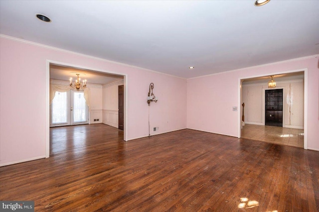 empty room with french doors, a chandelier, wood finished floors, and ornamental molding