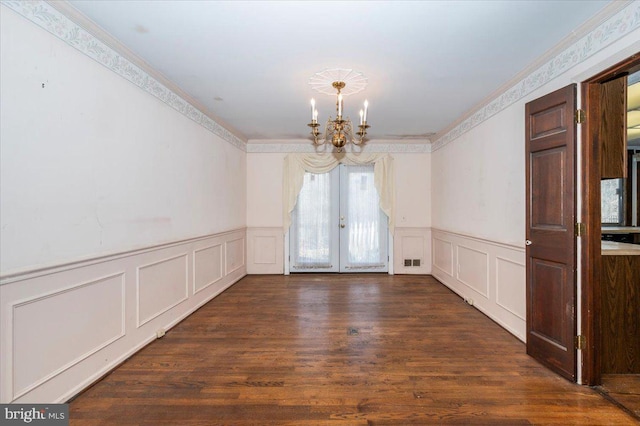 spare room with visible vents, a notable chandelier, ornamental molding, wood finished floors, and french doors