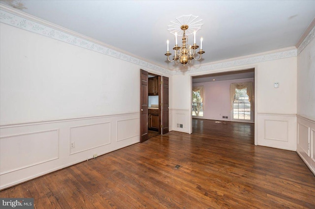 unfurnished dining area featuring wood finished floors, visible vents, an inviting chandelier, wainscoting, and crown molding