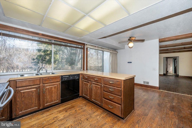 kitchen featuring visible vents, dark wood-type flooring, a sink, black dishwasher, and a peninsula