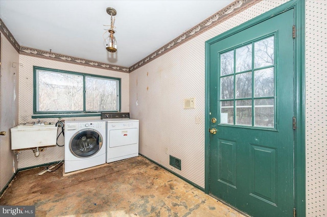 clothes washing area with visible vents, wallpapered walls, laundry area, independent washer and dryer, and a sink