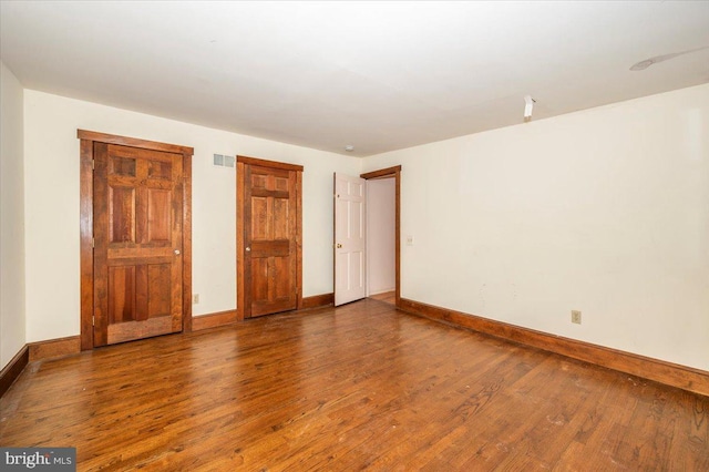 unfurnished bedroom with visible vents, baseboards, and wood-type flooring