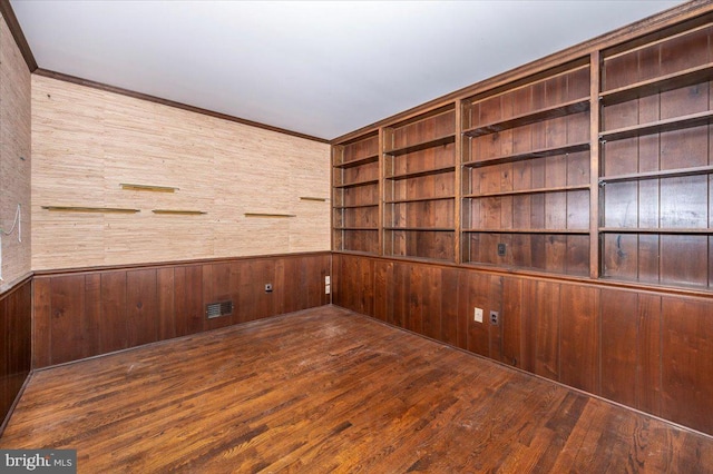 unfurnished room featuring hardwood / wood-style floors, visible vents, and wood walls